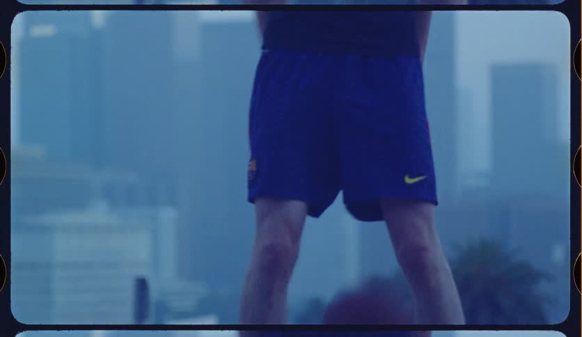 Vintage film shot of a man in athletic shorts dribbling a basketball against a foggy urban backdrop