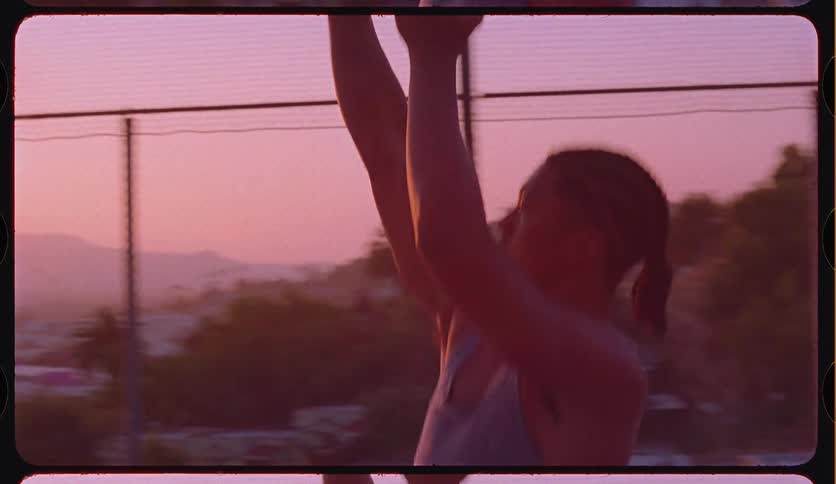 Slow motion footage of a young man shooting a basketball on a neighborhood court against a beautiful sunset