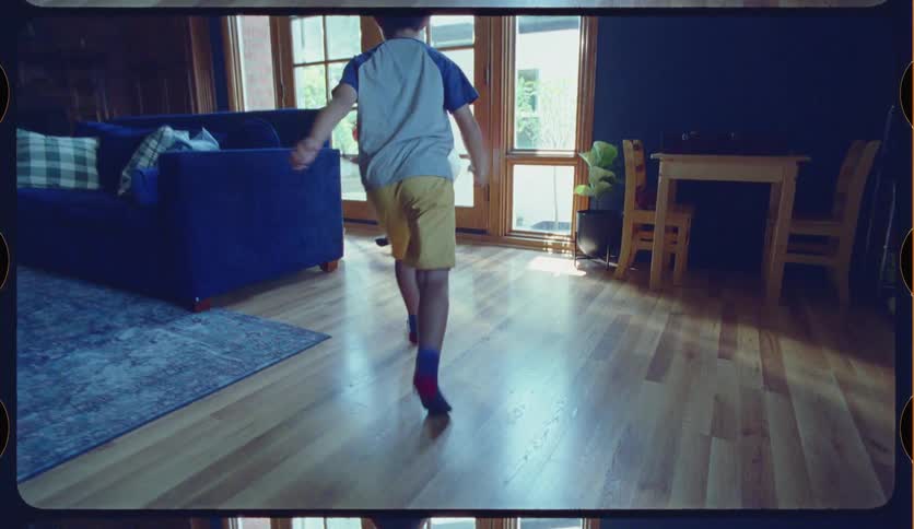 Brother and sister play with a toy basketball hoop in their living room, taking turns shooting a red ball in slow motion with a vintage 8mm film aesthetic