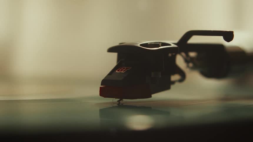 A close-up, static shot of a turntable stylus riding the grooves of a spinning vinyl record