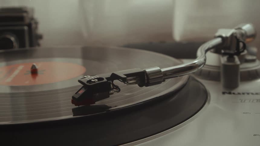 A vintage record player spins a vinyl disc in a close-up, nostalgic shot