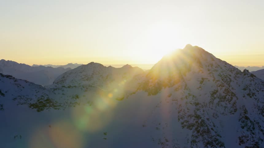 Sunlight shines over snowy mountains at sunset
