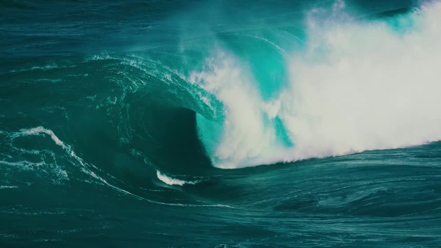 The immense power of a giant turquoise ocean wave is captured in mesmerizing slow motion as it builds and crashes spectacularly