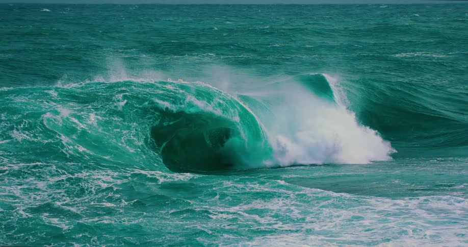 A powerful turquoise ocean wave curls and crashes in dramatic super slow motion, showcasing the raw energy of nature