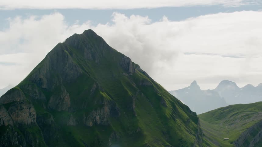 The green mountains come up at a point in the clouds