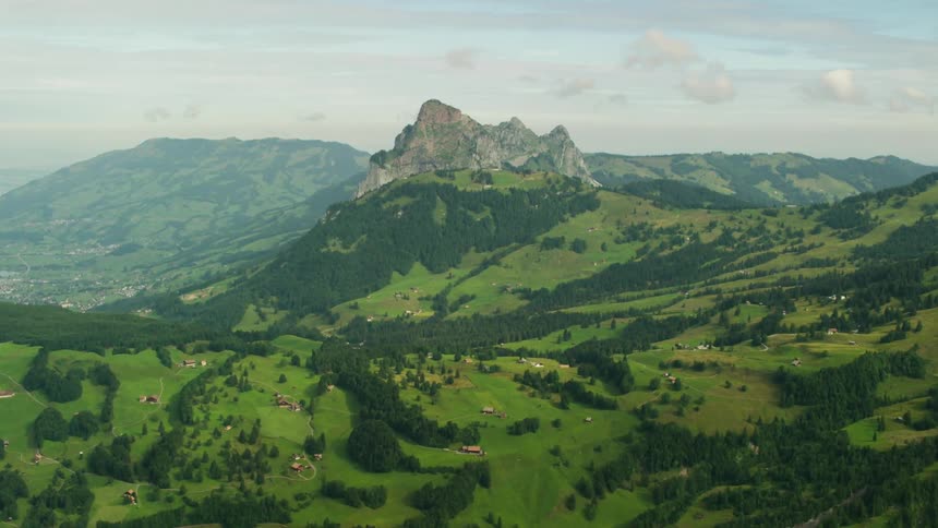 Green grass and trees lead up to a rocky peak