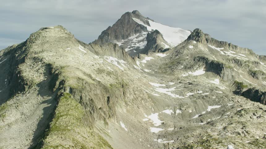 A snow-capped mountain ridge under a cloudy sky