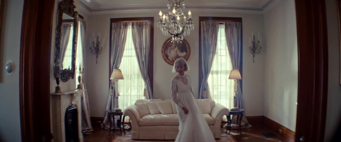 An elegant elderly woman slowly twirls in her beautiful white wedding gown while reminiscing in a grand, sunlit room
