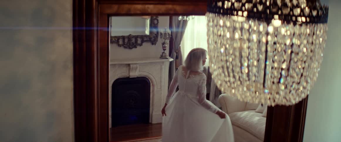A beautiful elderly woman in a vintage wedding dress smiles and twirls in slow motion inside an elegant mansion