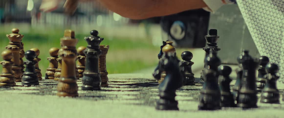 Close up of a hand moving chess pieces during a tense game in the park