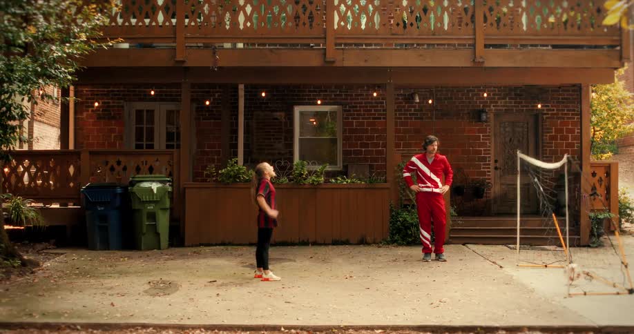 A daughter scores a goal in slow motion against her father, who is dressed as a retro goalie in their backyard