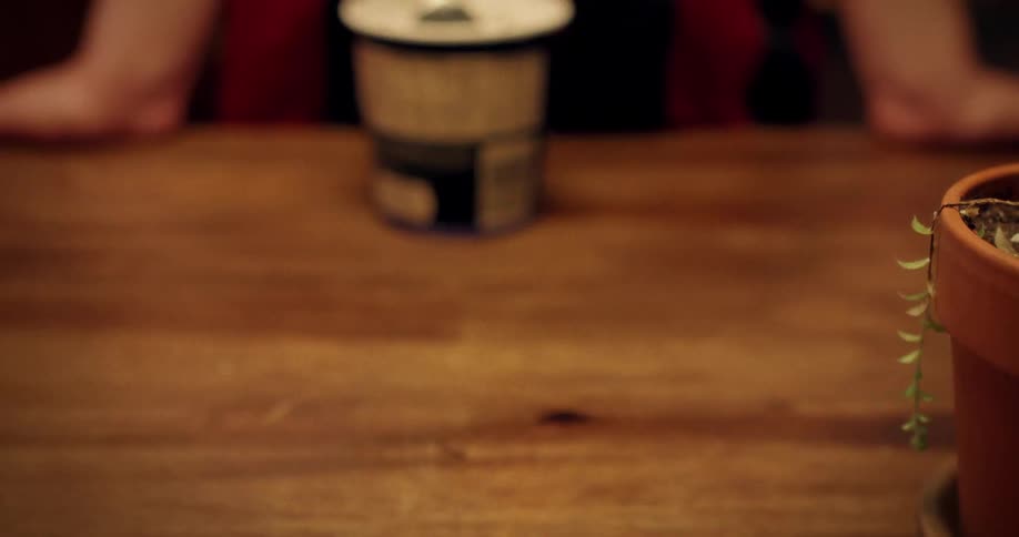 A slow-motion close-up shot shows a hand taking a spoonful of cookies and cream ice cream from a pint