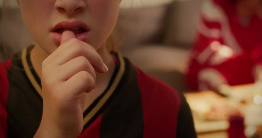 A close-up cinemagraph captures a young girl biting her fingernails in nervous anticipation