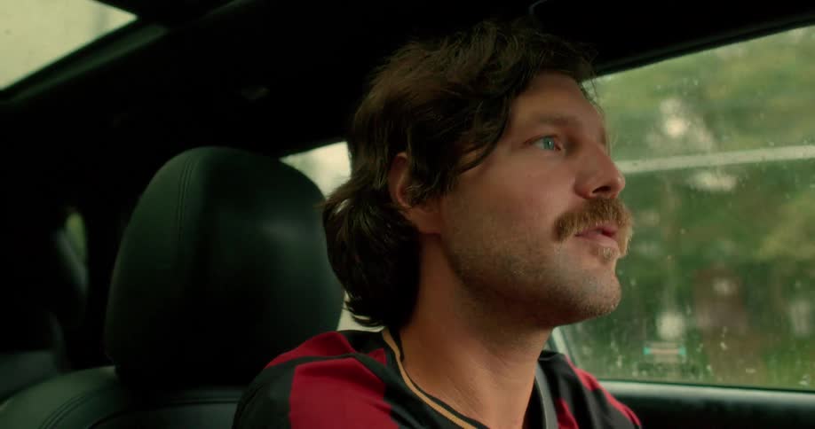 Close-up profile of a thoughtful man with a mustache driving his car during a rainy day