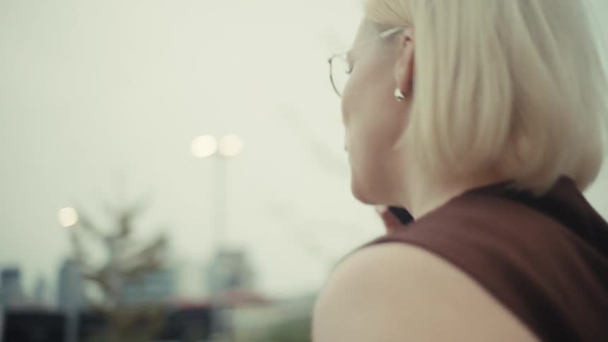 Cinematic slow-motion shot of a stylish blonde woman arguing on her phone in an urban setting