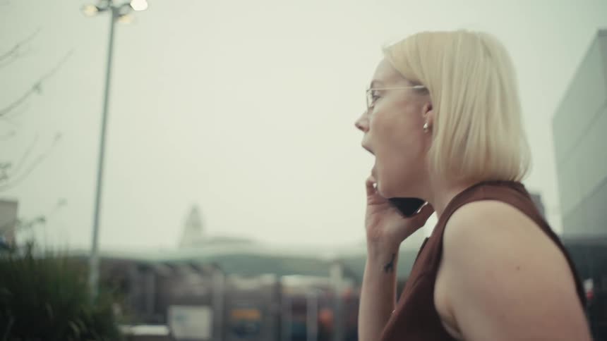 A stylish businesswoman gets a surprising phone call in the city, and her expression shifts from serious to pure joy