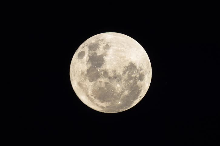 A detailed timelapse captures the full moon rising and moving across the pitch-black night sky