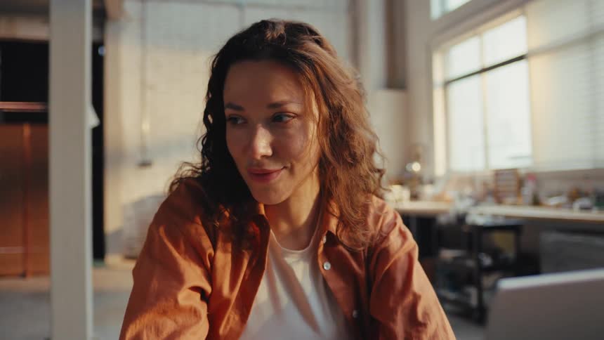 A beautiful young woman awakens from a short nap at her sun-drenched workspace and smiles