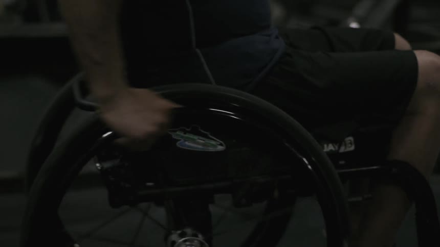 A man in a wheelchair moves in a gym
