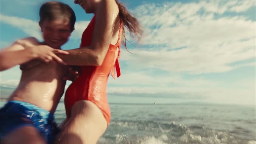 From a water-level perspective, a happy family splashes each other while playing in the sunlit ocean