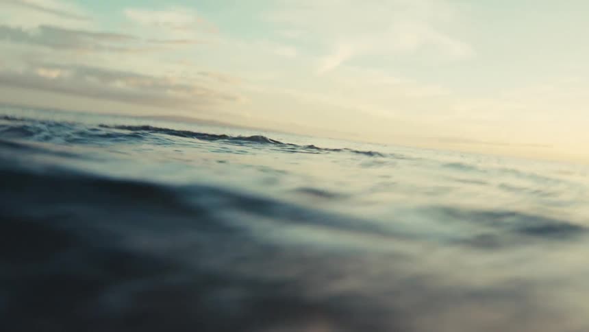 Immersive point-of-view of being caught in an ocean wave, from the initial crash to being submerged and resurfacing to a calm sea at dusk