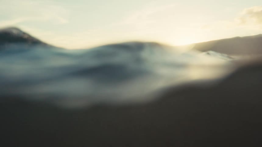 A low-angle view from the ocean surface slowly sinks into the dark depths below at sunset