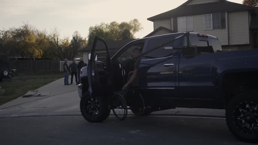 A wheelchair is lowered to the ground with a truck crane