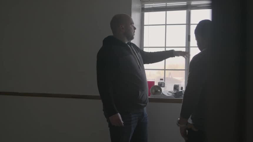 Men talk in front of a sunny window