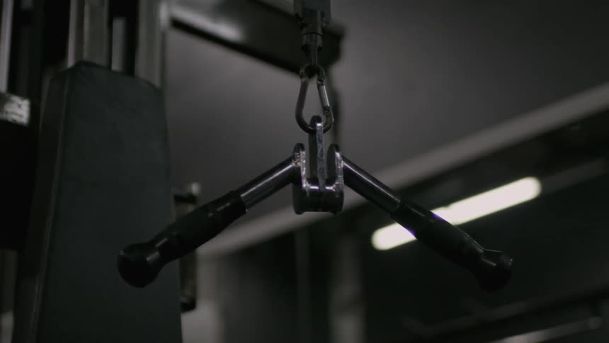 Metal bars dangle from a weight machine at the gym