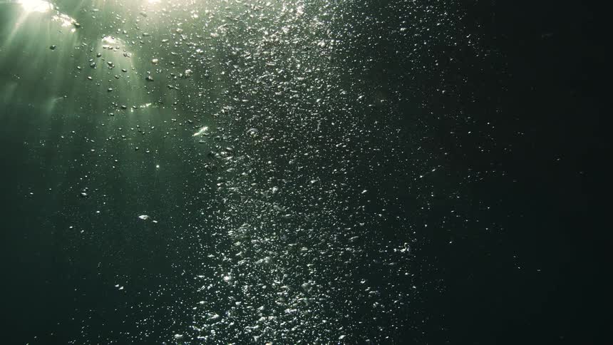 Mysterious underwater scene with thousands of bubbles rising to the surface, illuminated by shimmering sunbeams