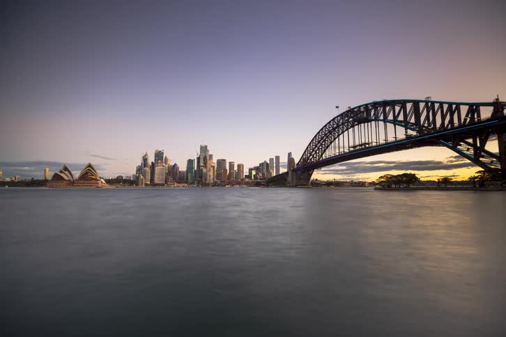 A stunning day-to-night time-lapse of the Sydney skyline, featuring the Harbour Bridge and Opera House illuminated by a vibrant light show