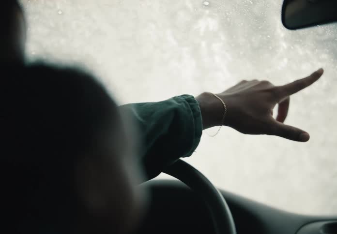 An over-the-shoulder slow-motion shot of a father and son driving through an automatic car wash, where the son playfully points at the soapy windshield