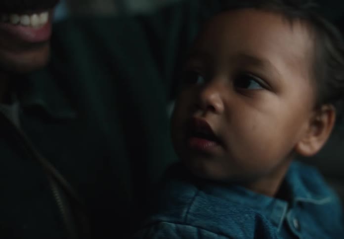 An adorable toddler sits on his father's lap in the car, looking around with wide-eyed curiosity in a tender moment