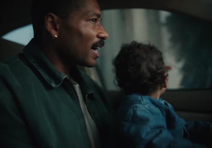 A close-up of a loving father and his curious toddler son bonding as they sit together in the driver's seat of a car, looking out the window with wonder