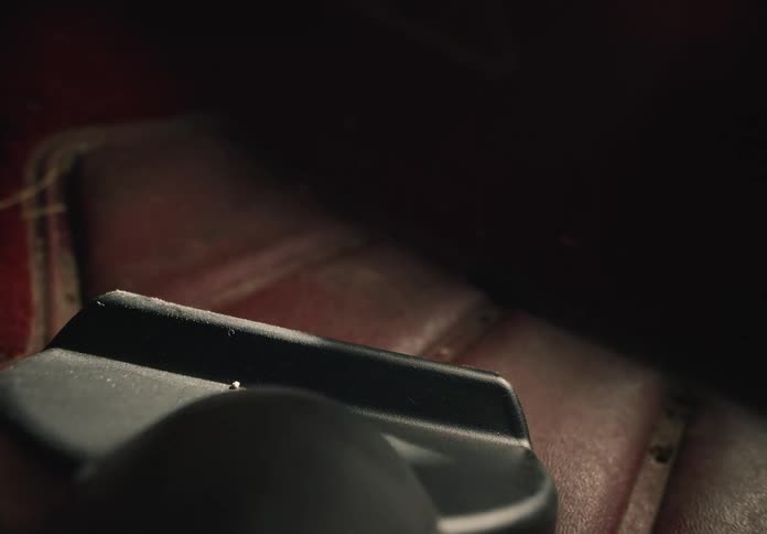 A detailed macro shot shows a vacuum cleaner nozzle cleaning the dust off a red car floor mat