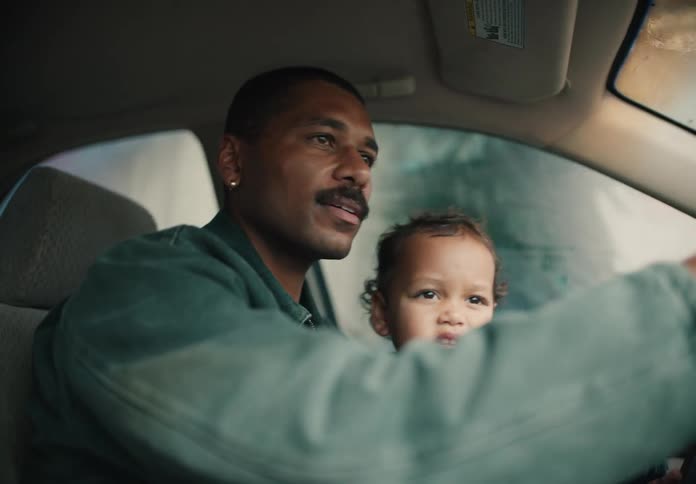 A loving father shares a fun moment with his toddler as they go through an automatic car wash together