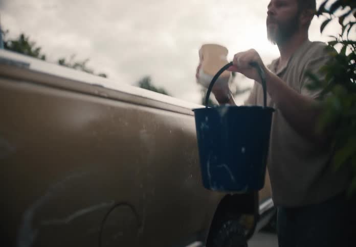 A father and son share a bonding moment as they wash their vintage pickup truck together in the driveway