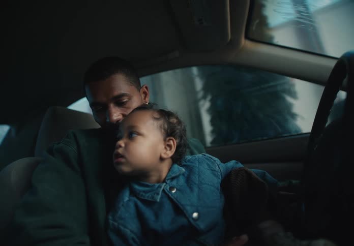 A loving father holds his curious toddler on his lap while they watch the machinery of an automatic car wash from inside their vehicle
