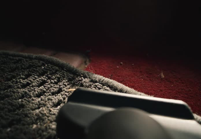 Detailed slow-motion footage shows a vacuum cleaner nozzle cleaning a vehicle's carpeted floor mat