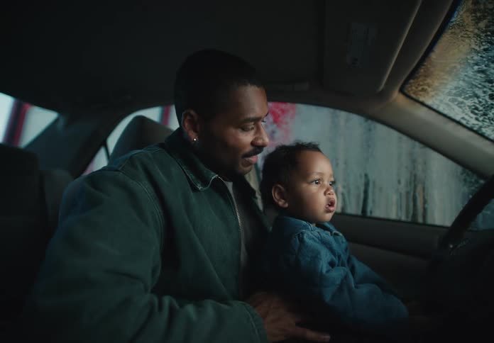 A loving father and his curious toddler watch in amazement as their car goes through an automatic car wash