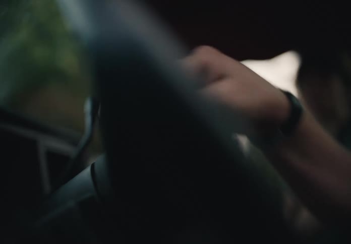 A person's hand carefully wipes down the leather steering wheel of a car with a cloth