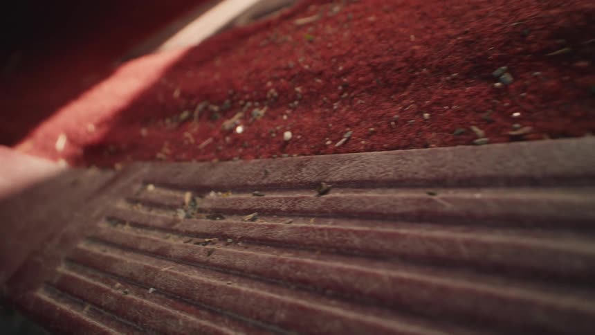 A macro shot slowly pans across the dirty, dusty red carpeted floor of a vintage vehicle's interior