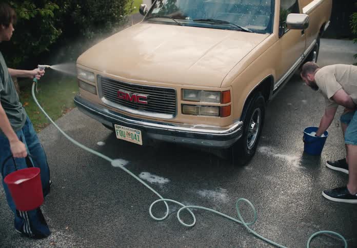 A father and son team up to wash their classic pickup truck in the driveway in slow motion