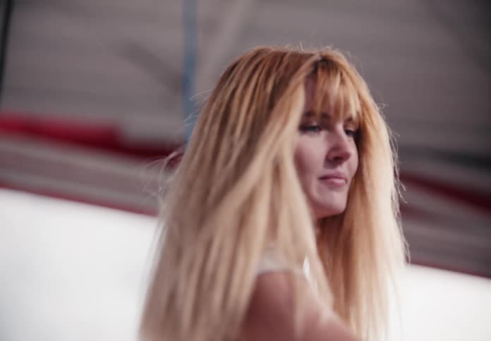 A slow-motion close-up of a blonde woman's face and hair as she moves at a self-service car wash