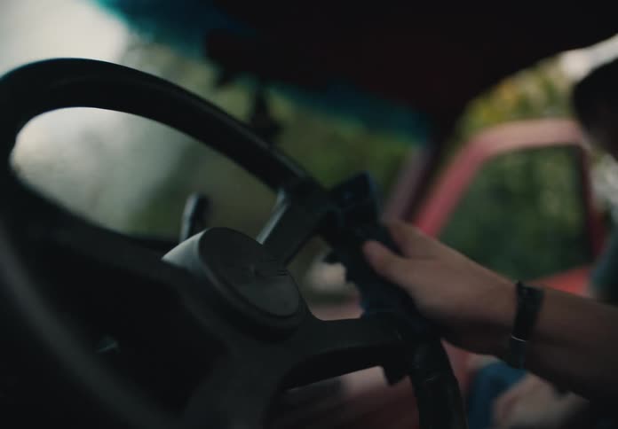 A man's hand carefully wipes down the steering wheel of his old pickup truck with a cloth