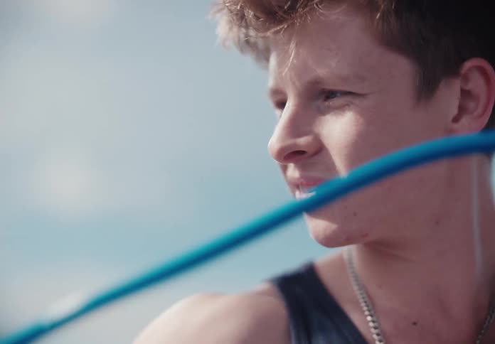 Close-up slow motion shot of a determined young man exercising outdoors with a jump rope