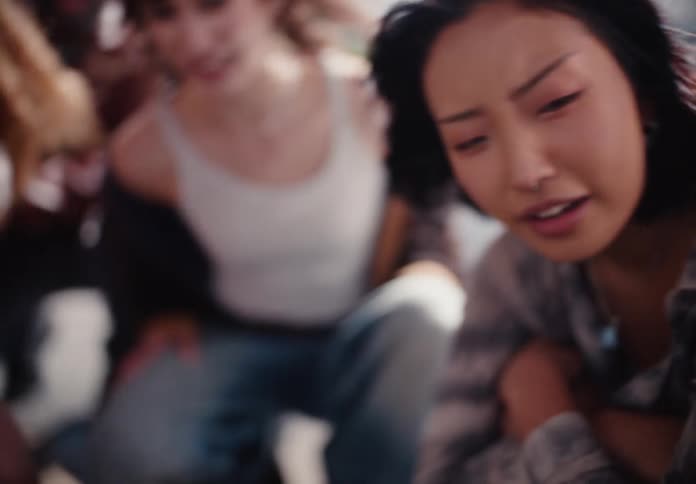 A passionate young Asian woman with a nose ring shouts with emotion in slow motion with a friend in the background