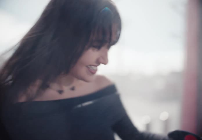 A beautiful brunette woman smiles and laughs while squinting in the bright sunshine in this slow motion close up