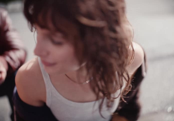 High angle slow motion close up of a pretty young woman with wavy brown hair smiling and laughing with her friends outdoors