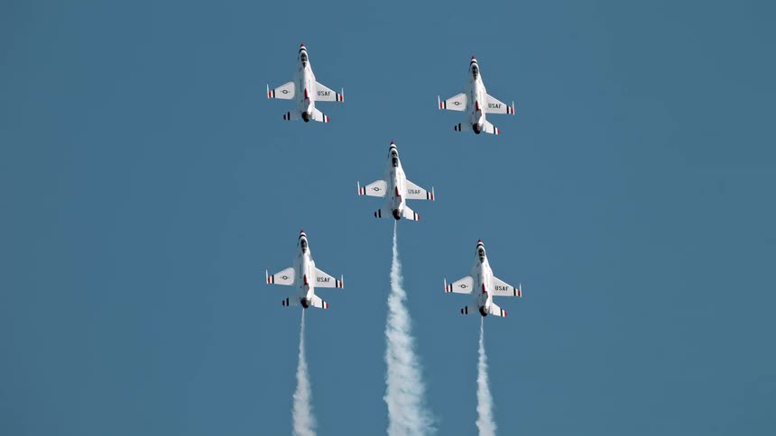 A squadron of five jets flies in precise formation against a clear blue sky in stunning slow motion